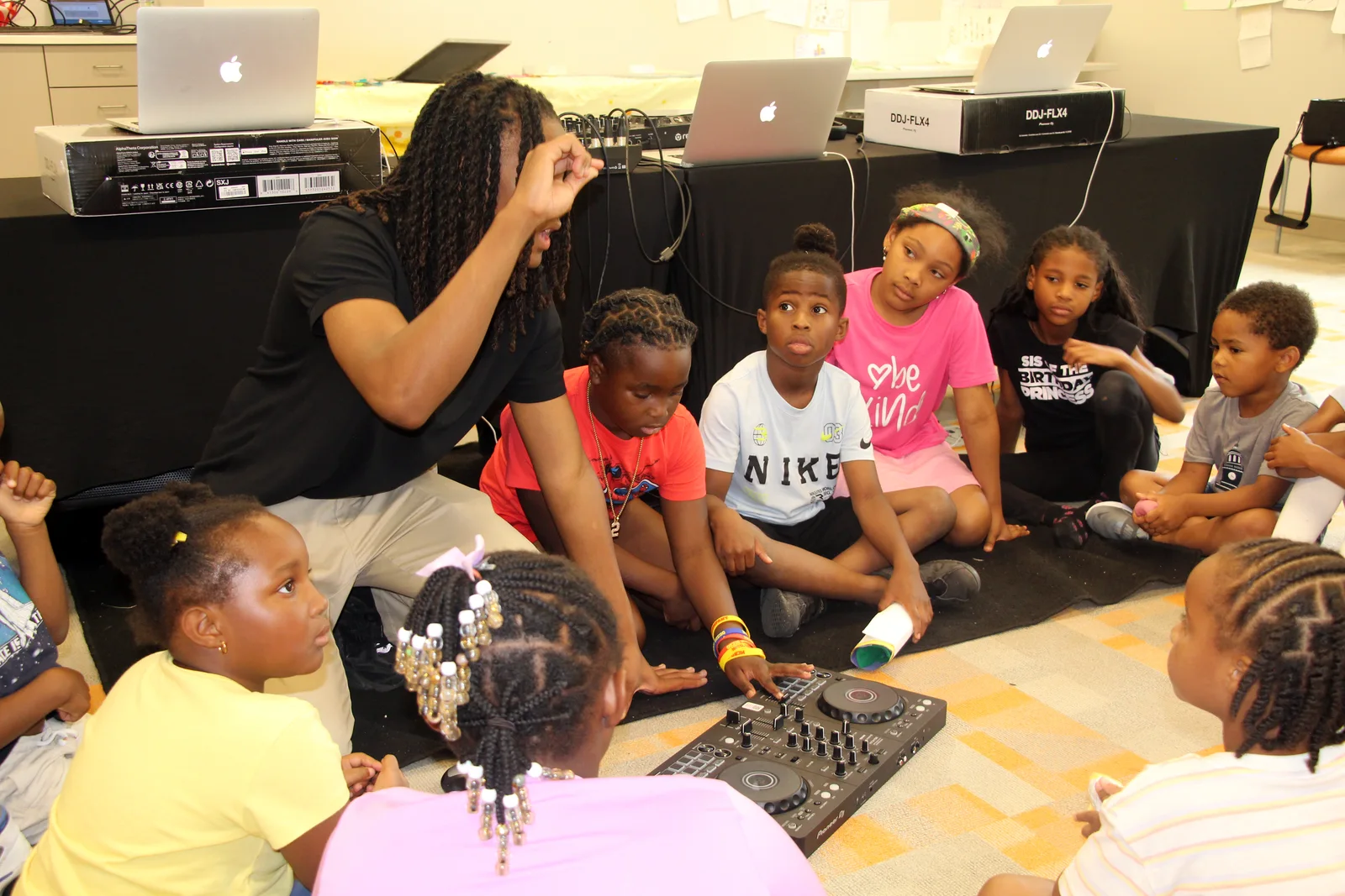 An instructor and young students exploring a DJ controller together